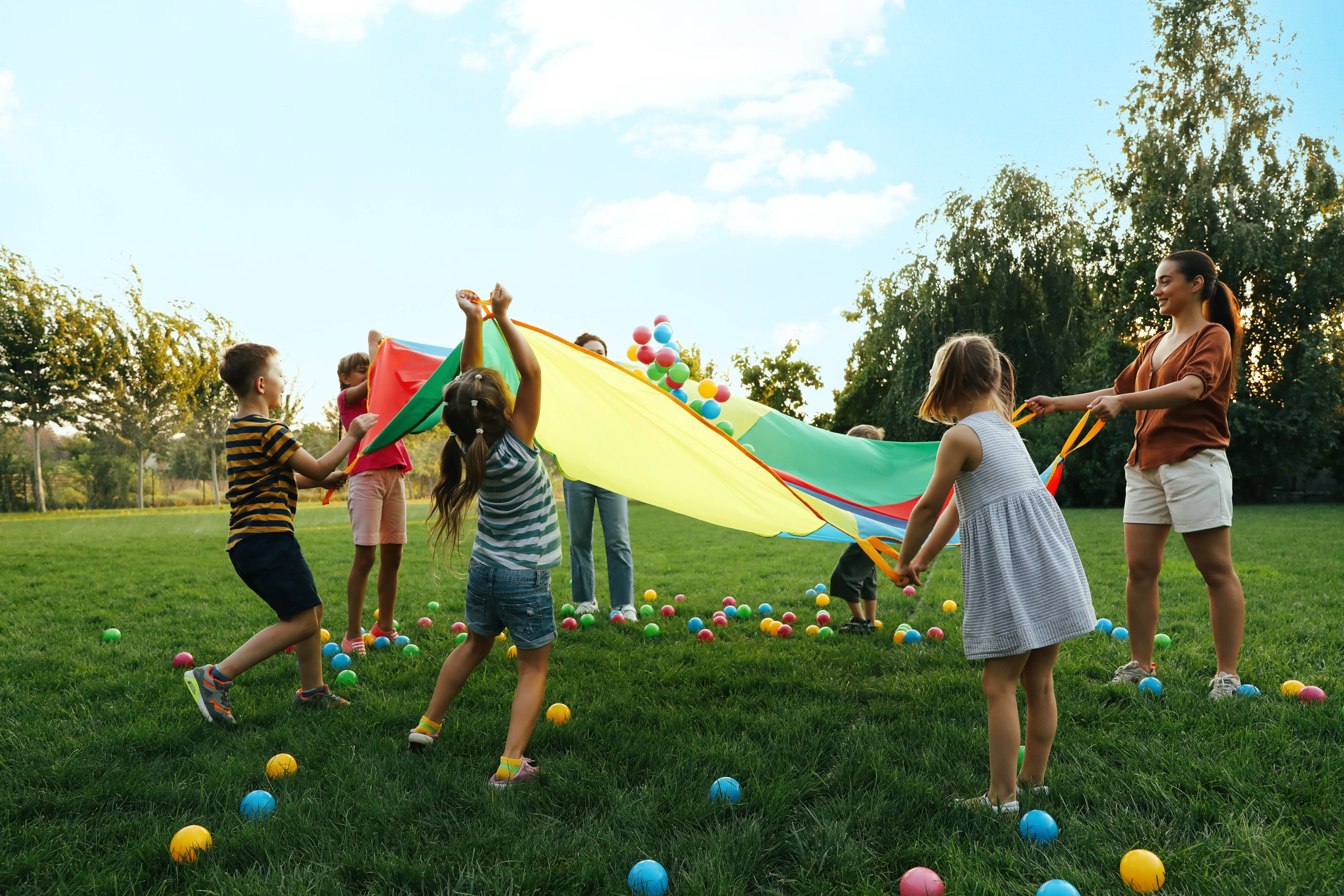 Kinder mit buntem Schwungtuch und Bällen
