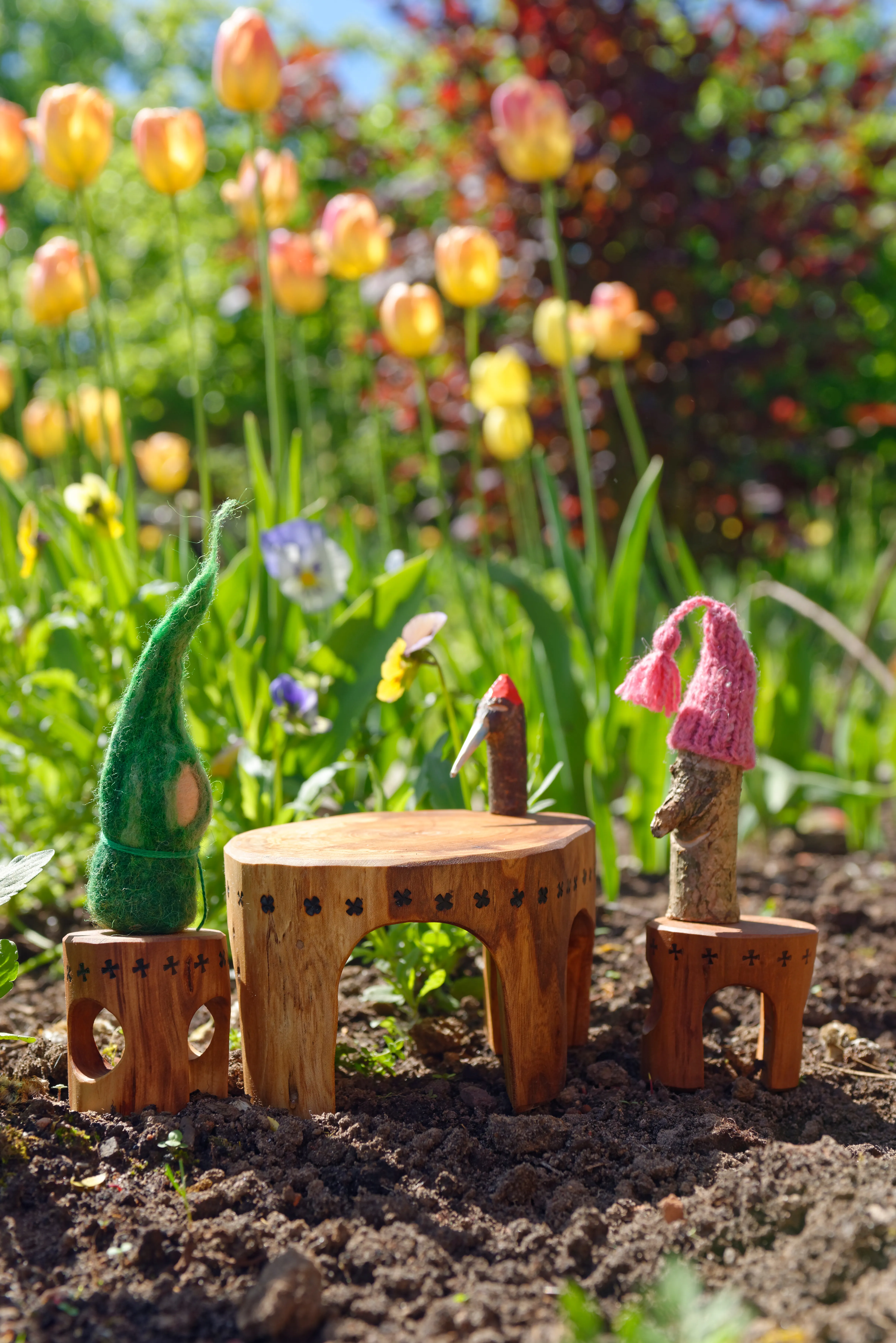 Kleine Filzpüppchen vor Tulpen im Schulgarten
