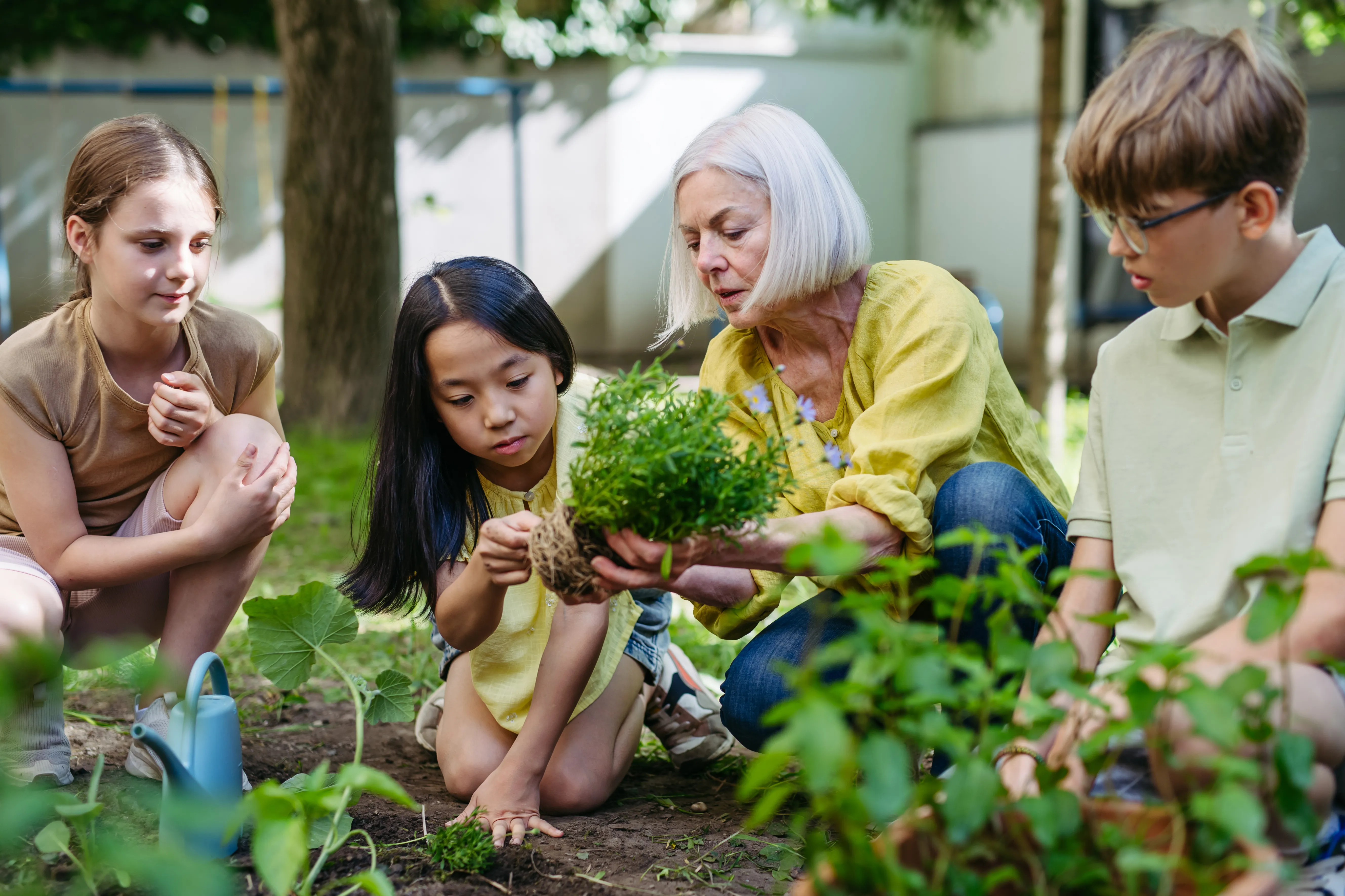 Lehrerin pflanzt mit Kindern im Schulgarten