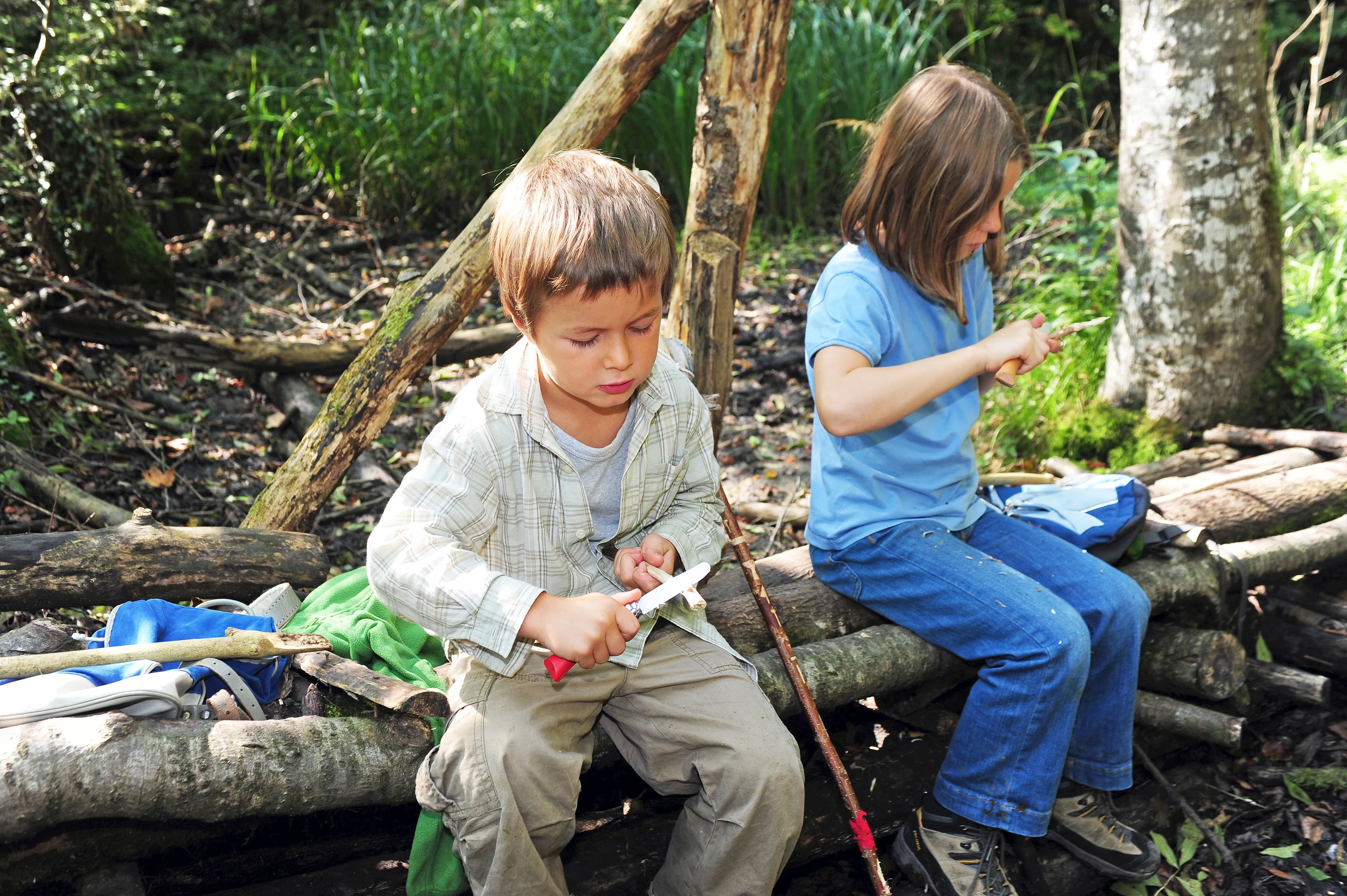 Zwei Kinder im Wald beim Schnitzen
