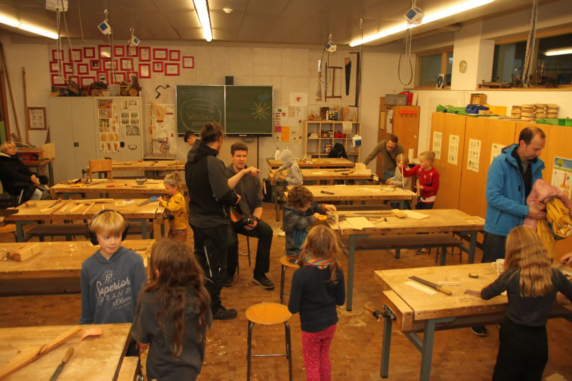 Kinder und Erwachsene arbeiten gemeinsam im Werkraum der Schule